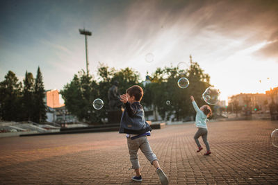 Full length of children playing against sky during sunset