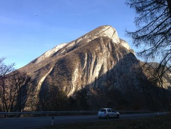 Cars on road by mountain against blue sky