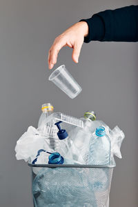 Close-up of hand holding bottle against gray background