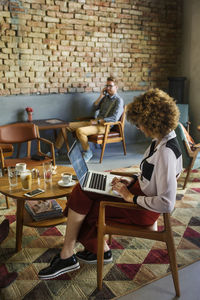 Side view of businesswoman using laptop in hotel lobby