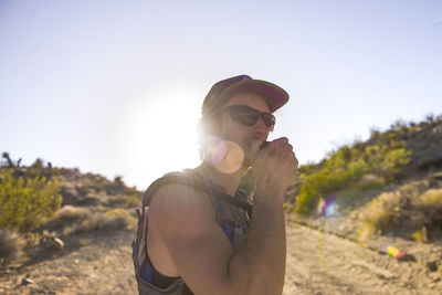 Hiker talking through walkie in front of sunset, blue sky and desert