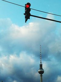 Low angle view of communications tower against cloudy sky