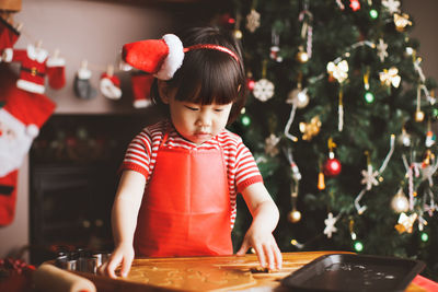 Girl standing with cookie on table 