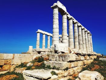 Low angle view of ancient greek temple against blue sky