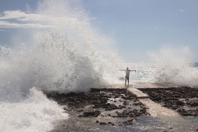Scenic view of furious sea waves splashing on shore against sky