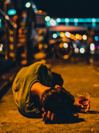 Close-up of man sitting on street at night