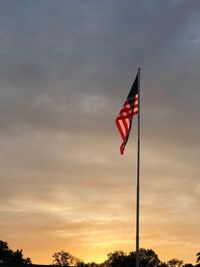 Low angle view of flag flags against sky during sunset