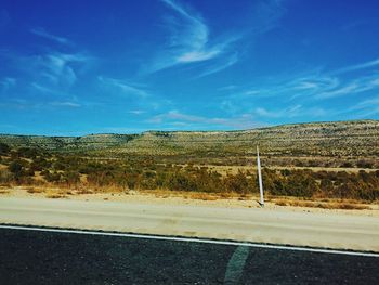 Road by trees against blue sky