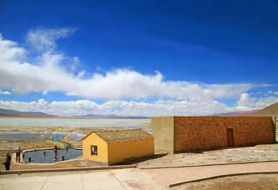 Houses by sea against blue sky