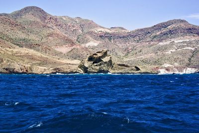 Scenic view of sea and mountains against clear blue sky