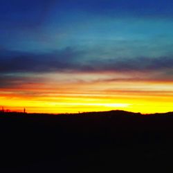 Silhouette landscape against dramatic sky during sunset