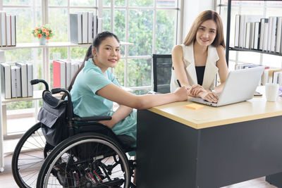 Young woman using phone while sitting on table