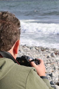 Rear view of man photographing sea