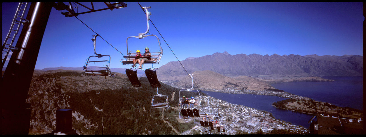 OVERHEAD CABLE CARS OVER MOUNTAINS AGAINST CLEAR SKY