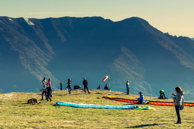 People at shore against mountains