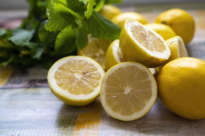 Group of wet lemons halves with mint leaves, on wooden colored table. close-up