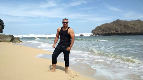 Full length portrait of young man standing on beach