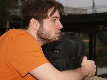 Side view of thoughtful young man with backpack looking away