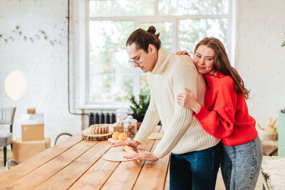 Young man and woman romantic couple couple hug at the kitchen while coocking and backing