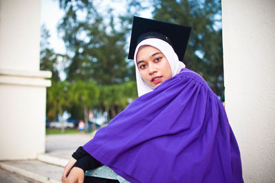 Portrait of beautiful young woman standing against wall