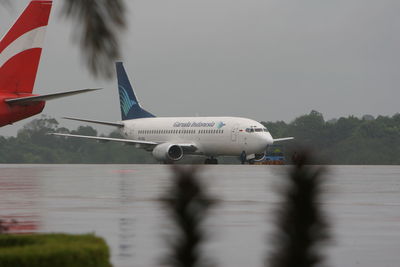 Airplane flying over airport runway against sky