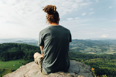 Rear view of man sitting on rock