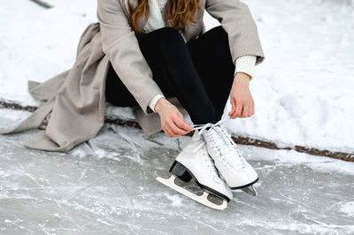 Pictured are hands tying ice skates. a young woman came to skate on an ice rink. winter fun