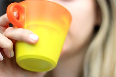 Close-up of woman hand holding yellow drink