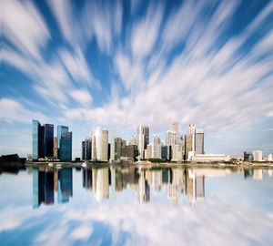 Reflection of buildings in calm water against sky