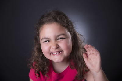 Portrait of young woman against black background