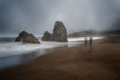 Scenic view of rocks on beach against sky