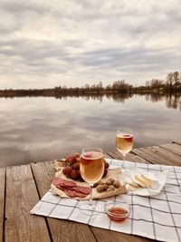 Breakfast on table by lake against sky