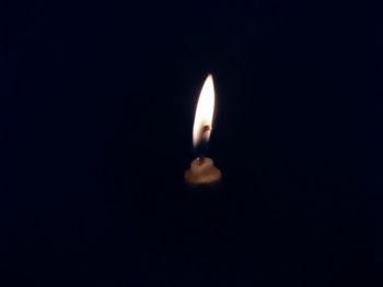 Close-up of lit candle in darkroom