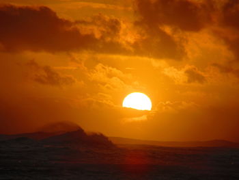 Scenic view of sea against dramatic sky during sunset