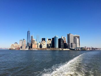 Skyscrapers in sea against clear sky