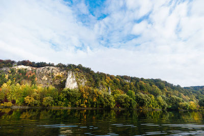 Trees growing on mountain by danube river against cloudy sky