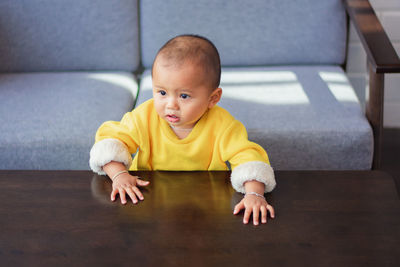 Portrait of the cute boy sitting on the hardwood floor at home