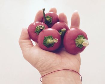 Close-up of hand holding strawberry over white background