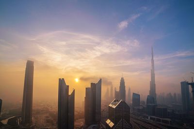 Modern buildings in city against sky during sunset