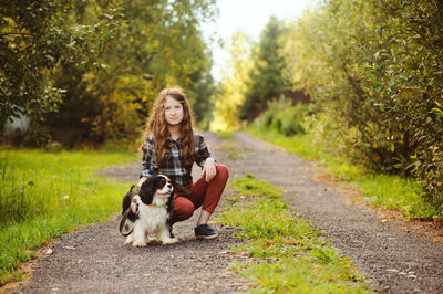 Young woman with dog on road by trees