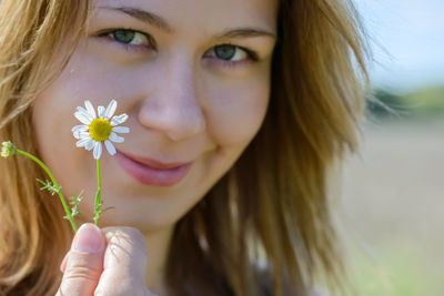Close-up portrait of beautiful woman holding red flower