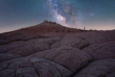 Silhouette of unrecognizable explorer standing on scenery of rocky formations in highlands under milky way starry sky in vermillion cliffs national monument, arizona in usa