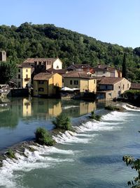 Buildings by river against clear sky