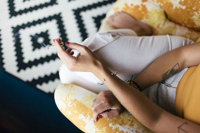 High angle view of woman smoking while sitting on sofa at home