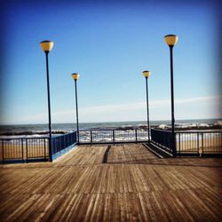 Street light by sea against clear sky