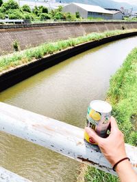 High angle view of person hand on grass by river