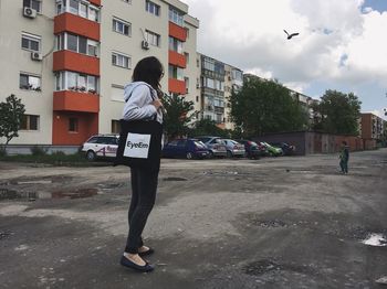 Rear view of woman standing on street in city