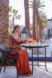 Full length of woman sitting by table at cafe