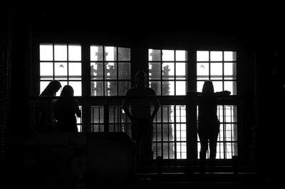 Silhouette people standing by window in darkroom