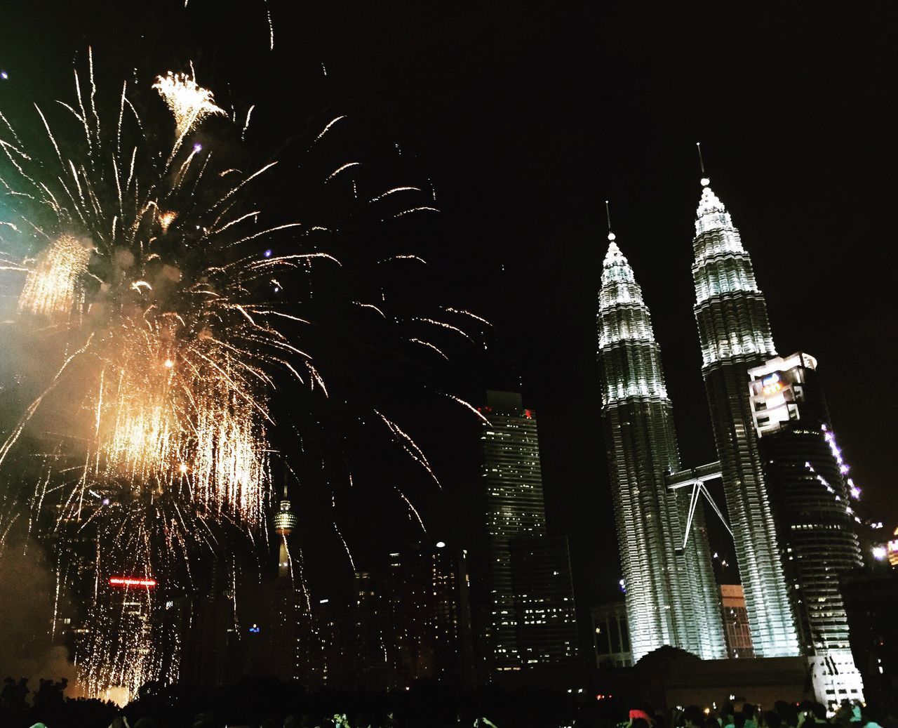 LOW ANGLE VIEW OF FIREWORK DISPLAY IN CITY AT NIGHT